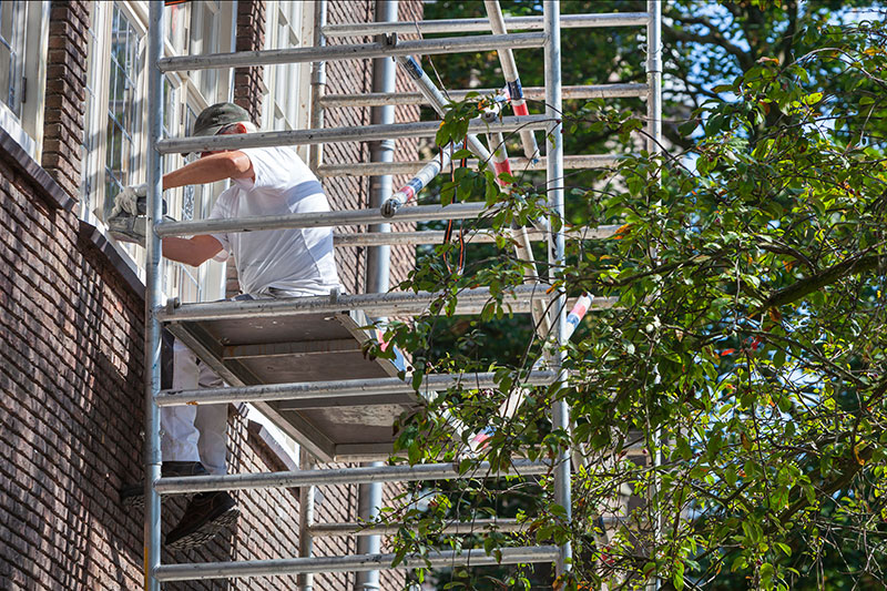 Professional painter with sander on a scaffolding